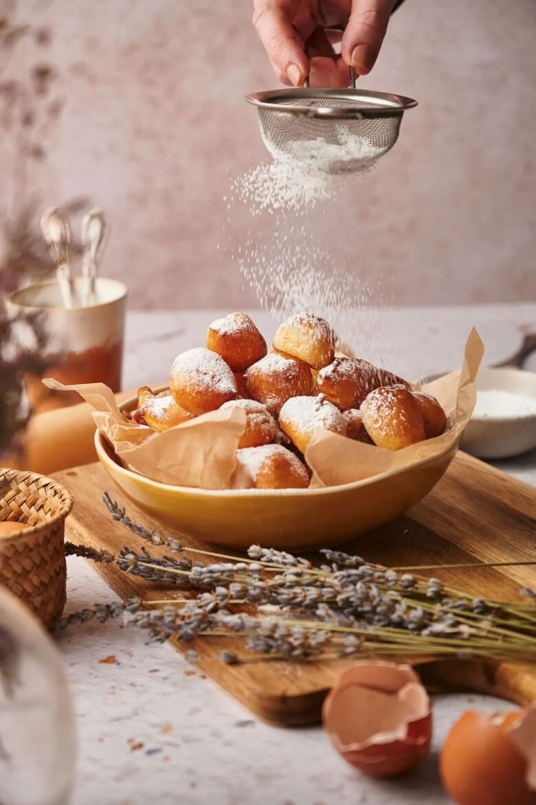 Zeppole mit Puderzucker bestäuben